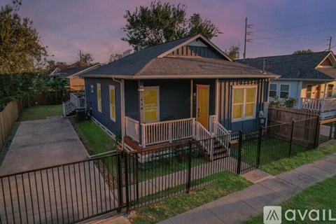 A small house with a front porch and a black fence.