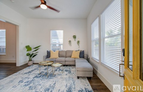 A living room with a couch, a rug, and a ceiling fan.
