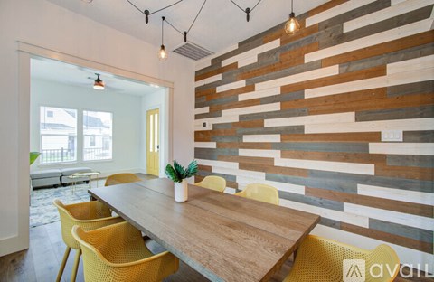 A wooden table with yellow chairs is in front of a wooden wall.