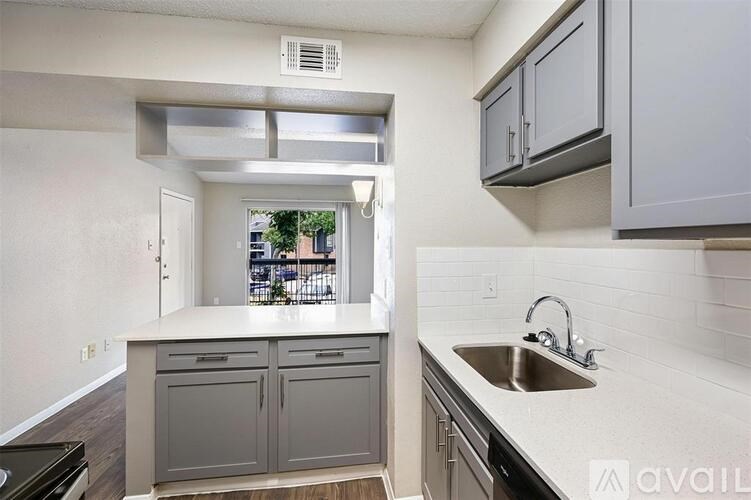A kitchen with a sink, cabinets, and a window.
