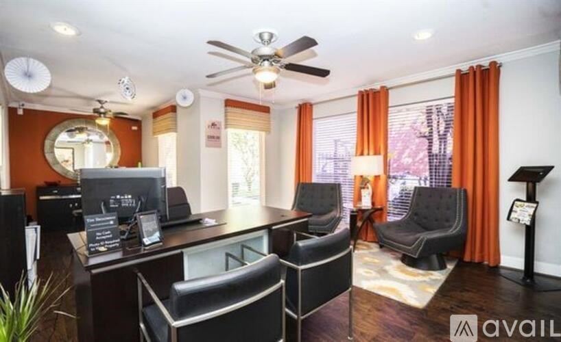 A modern office space with black furniture and a ceiling fan.