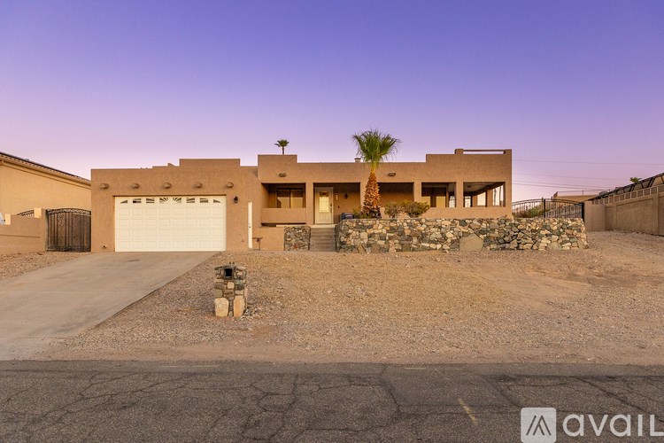 A house with a garage and a palm tree in front.