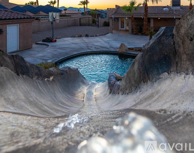 A pool with a waterfall in the middle of a backyard.