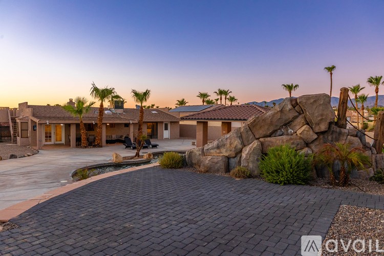 A house with a driveway and palm trees in front.