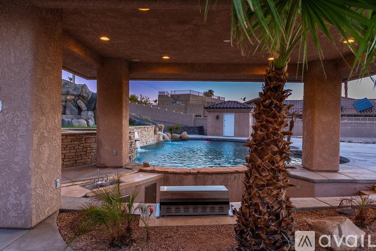 A pool surrounded by a stone wall and a palm tree.