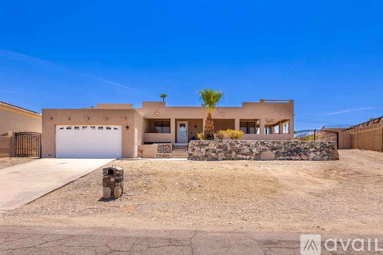 A modern house with a stone wall and a palm tree in front.