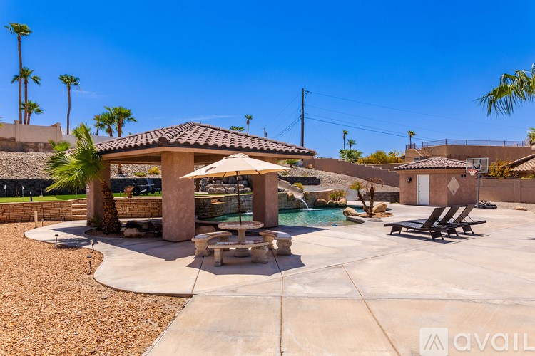 A pool area with a table and chairs and a palm tree.