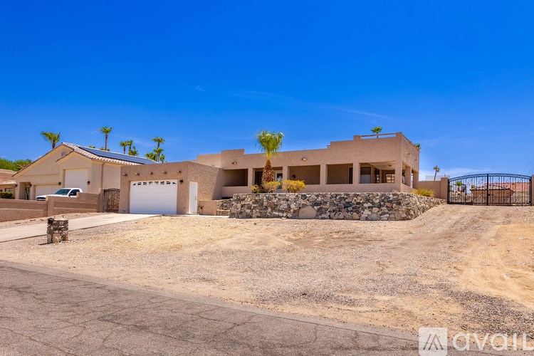 A house with a white garage door is surrounded by a stone wall and has a gate.