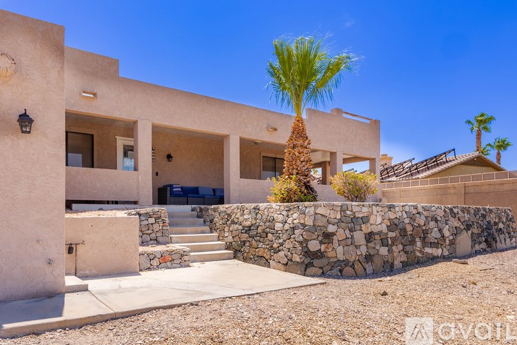 A modern house with a stone wall and a palm tree in front.