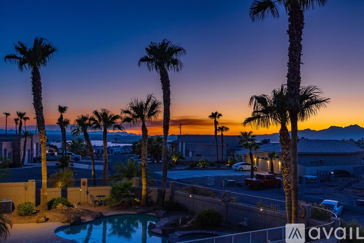 A pool surrounded by palm trees at sunset.