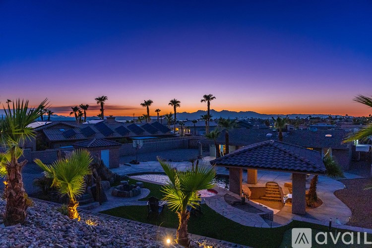 A beautifully lit outdoor area with palm trees and a gazebo at dusk.