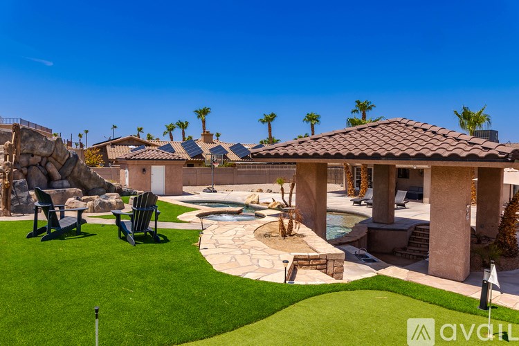 A house with a pool and lawn chairs in front.