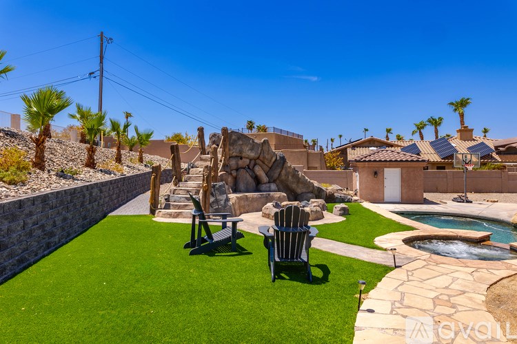 A backyard with a stone statue, a chair, and a pool.