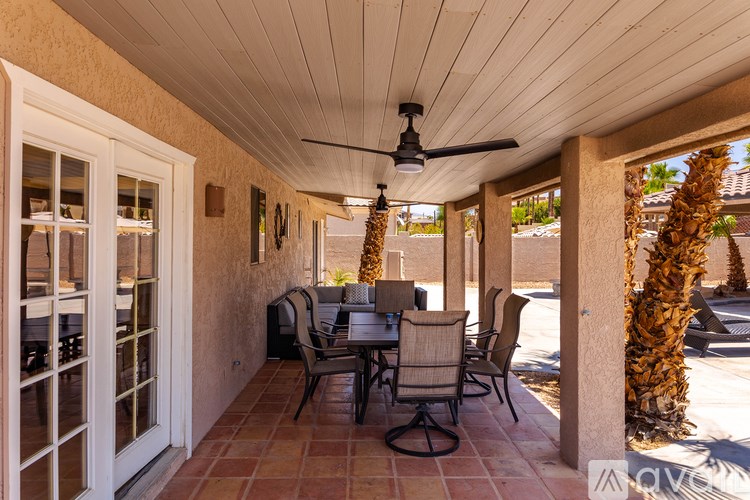A patio with a table and chairs is covered by a roof.
