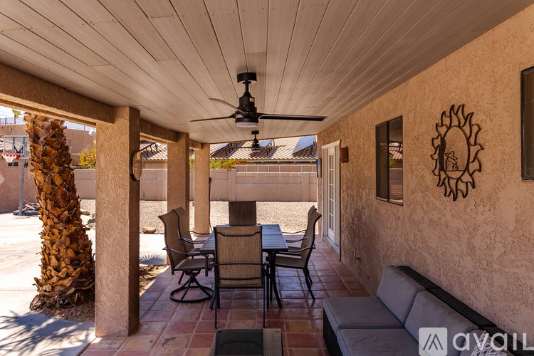 A patio with a table and chairs under a ceiling fan.