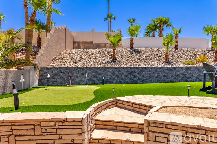 A backyard with a stone wall and palm trees.