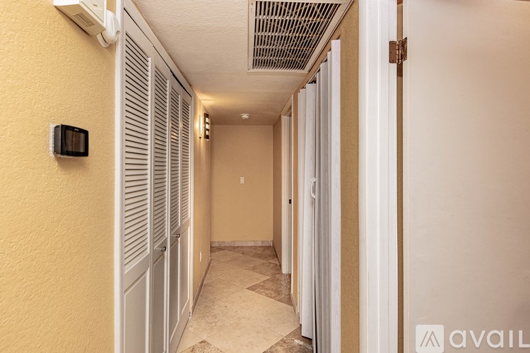 A hallway with a wall-mounted thermostat and a tiled floor.