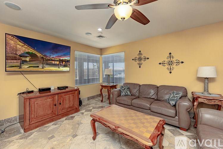 A living room with a brown leather couch, a wooden coffee table, and a ceiling fan.