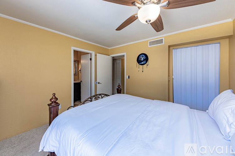 A bedroom with a bed, a ceiling fan, and a window with curtains.