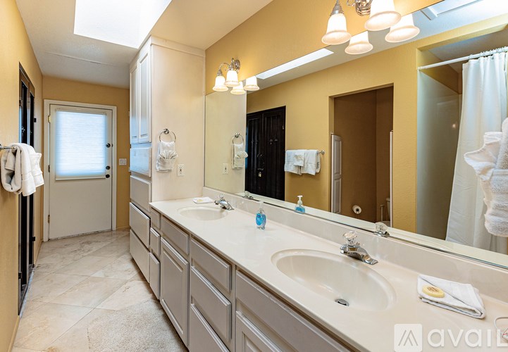 A bathroom with a vanity, sink, mirror, and lighting fixture.