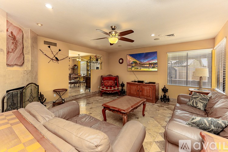 A living room with a brown leather couch and a ceiling fan.