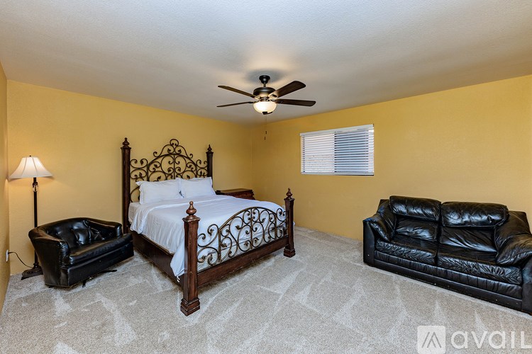 A bedroom with a bed, a couch, and a ceiling fan.