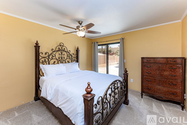 A bedroom with a bed, dresser, and ceiling fan.