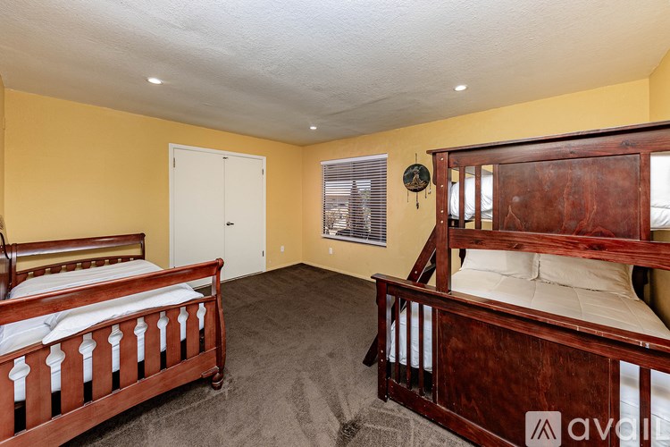 A bedroom with two beds and a window with blinds.