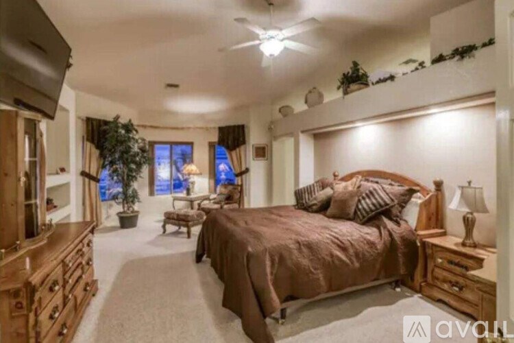 A bedroom with a large bed and a ceiling fan.