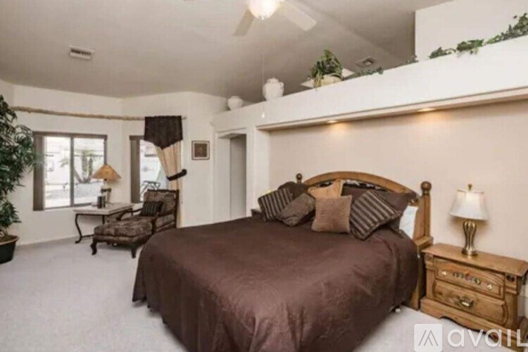A bedroom with a large bed and a chair by the window.