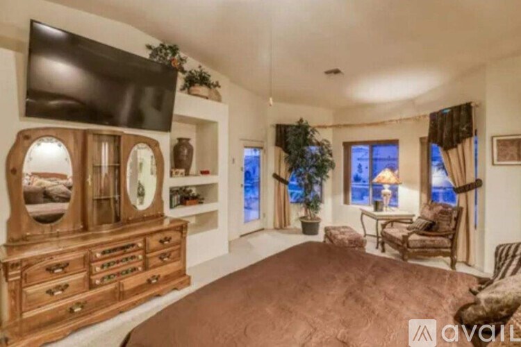A bedroom with a brown bedspread and a wooden dresser with a mirror.