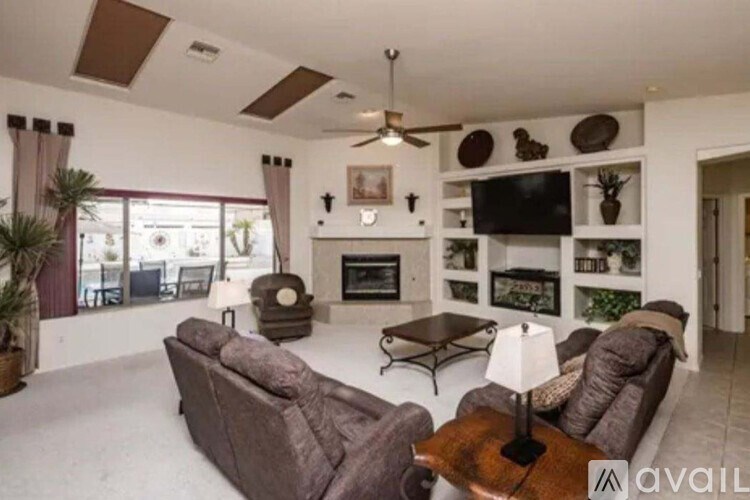 A living room with a brown couch, a fireplace, and a TV mounted on the wall.