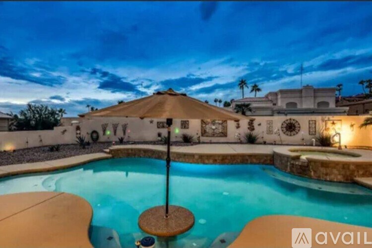 A pool with a brownish water and a brownish floor with a white wall and a building in the background.