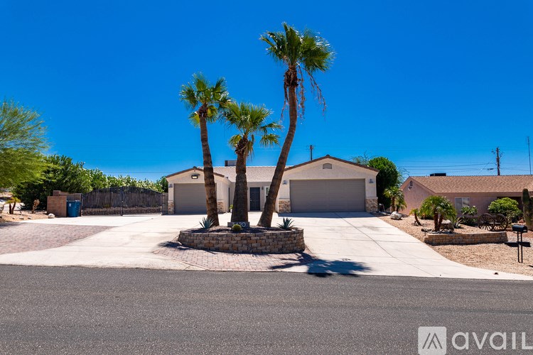 A house with a driveway and two palm trees in front.