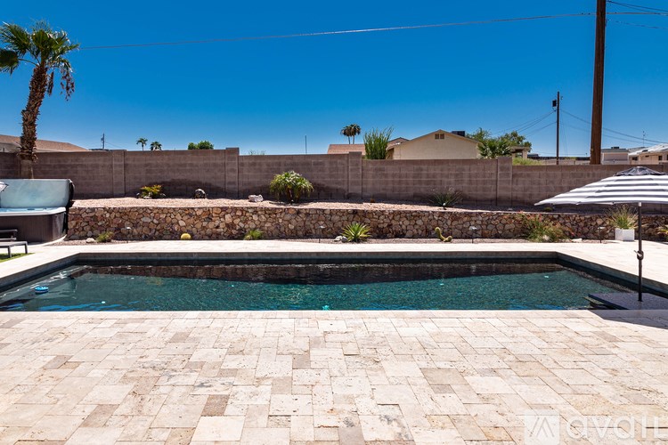 A pool surrounded by a stone wall and a patio.