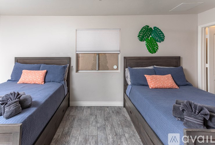 Two beds with blue bedspreads and pillows in a room.