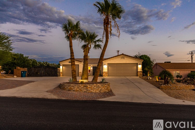 A house with a driveway and two palm trees in front.