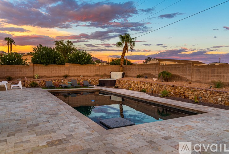 A pool surrounded by a stone wall with a sunset in the background.