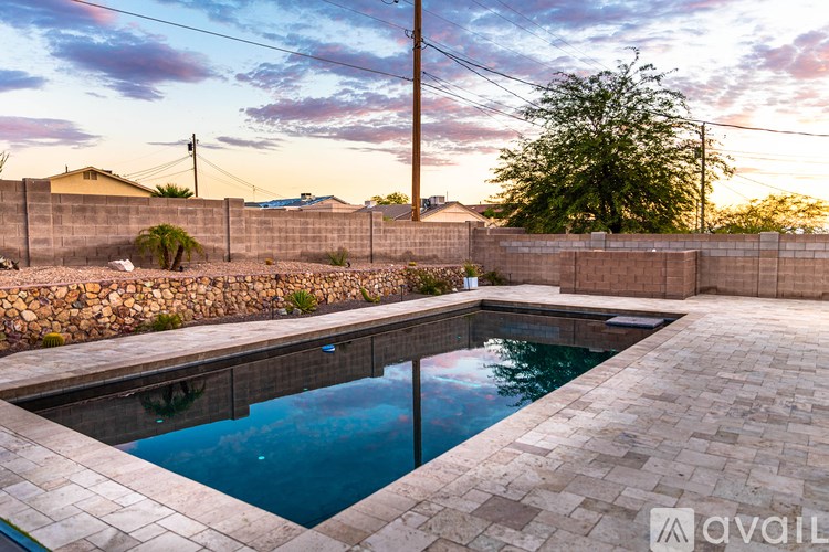 A pool surrounded by a stone wall and a wooden fence.
