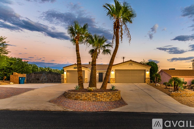 A house with a driveway and palm trees in front.