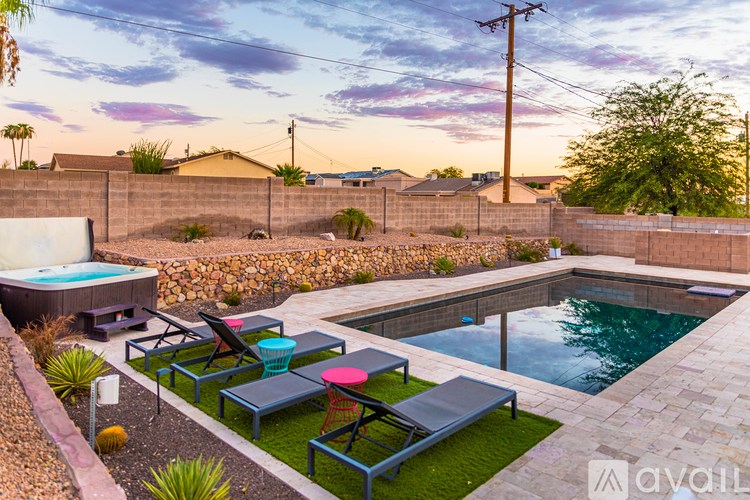 A backyard with a pool and lounge chairs.