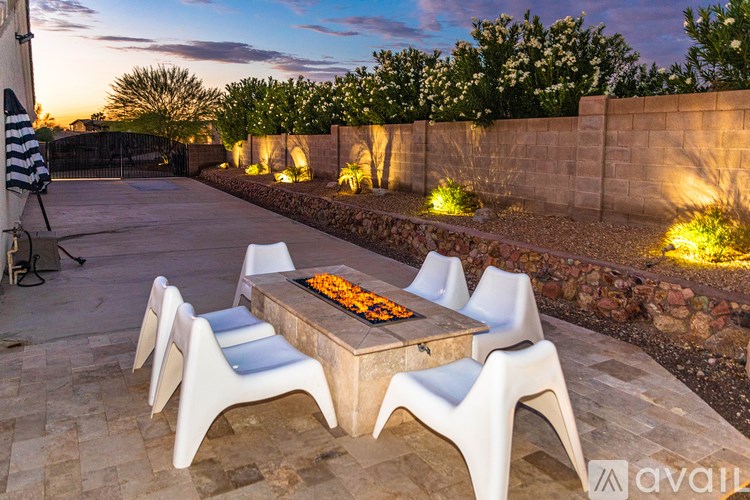 A table with chairs and flowers on it is lit by outdoor lights.