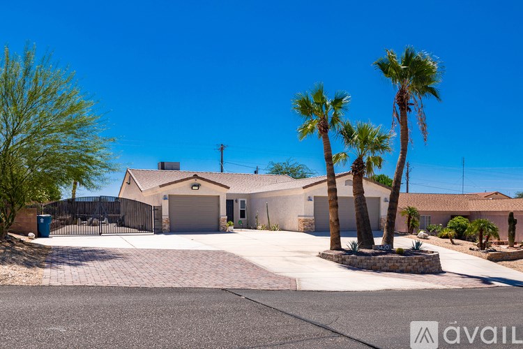 A house with a driveway and palm trees in front.