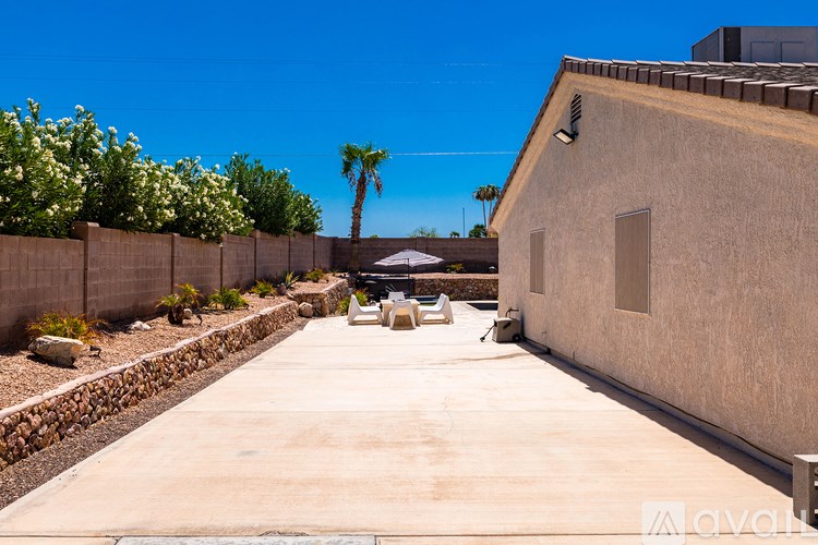 A concrete patio with a white umbrella and a wall of white flowers.