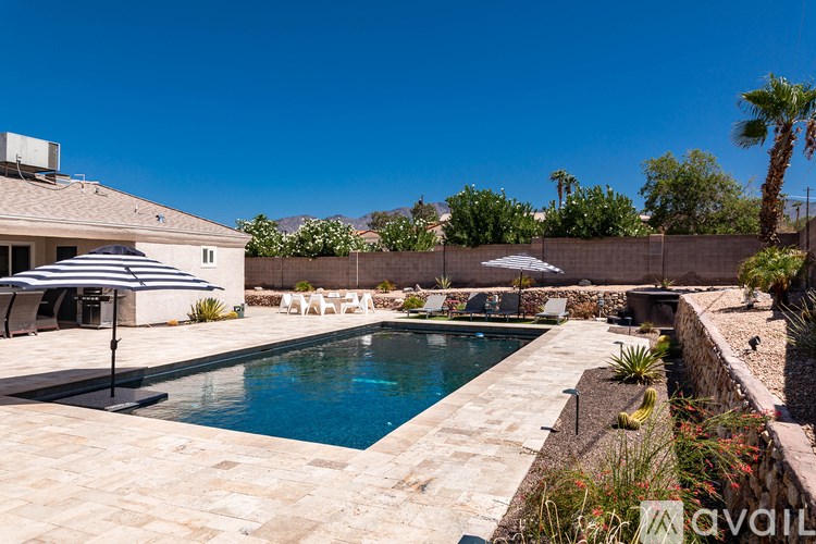 A pool surrounded by a stone wall and patio furniture.