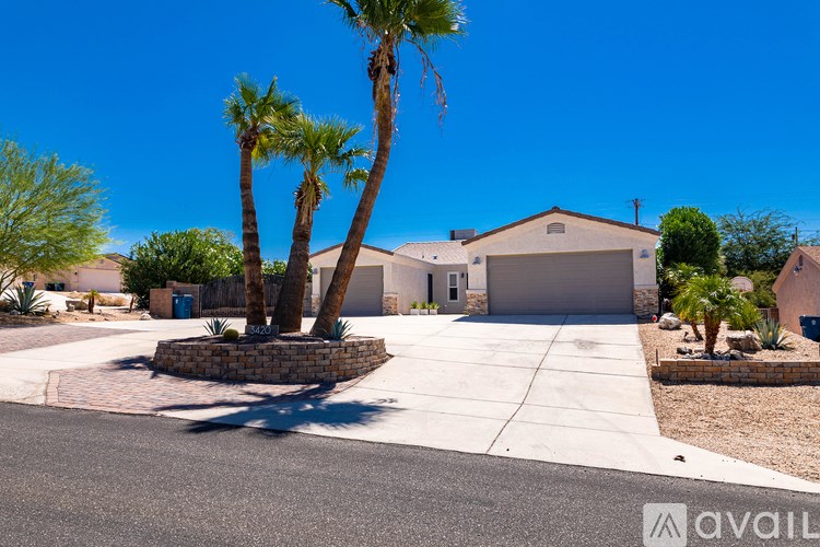 A house with a driveway and palm trees in front.