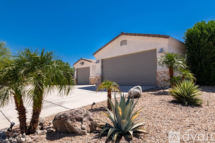 A house with a garage and a driveway with a rock and plants.