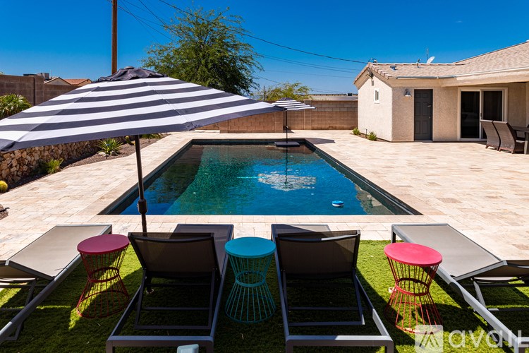 A striped umbrella shades a pool and lounge chairs.