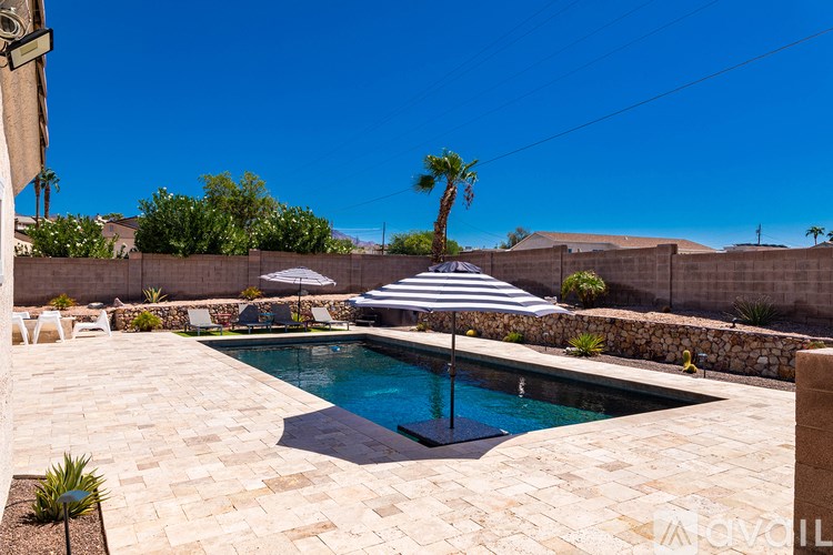 A pool surrounded by a stone patio and a wall.