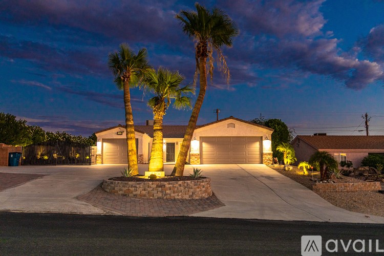 A house with a driveway and palm trees in front.